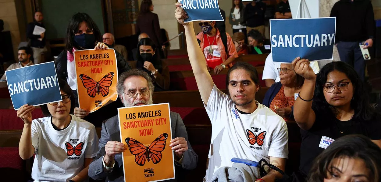 Pessoas seguram cartazes com a palavra “Sanctuary” enquanto o Conselho Municipal de Los Angeles se reúne para considerar a adoção de uma lei de “cidade santuário” na Prefeitura, em Los Angeles, Califórnia, Estados Unidos