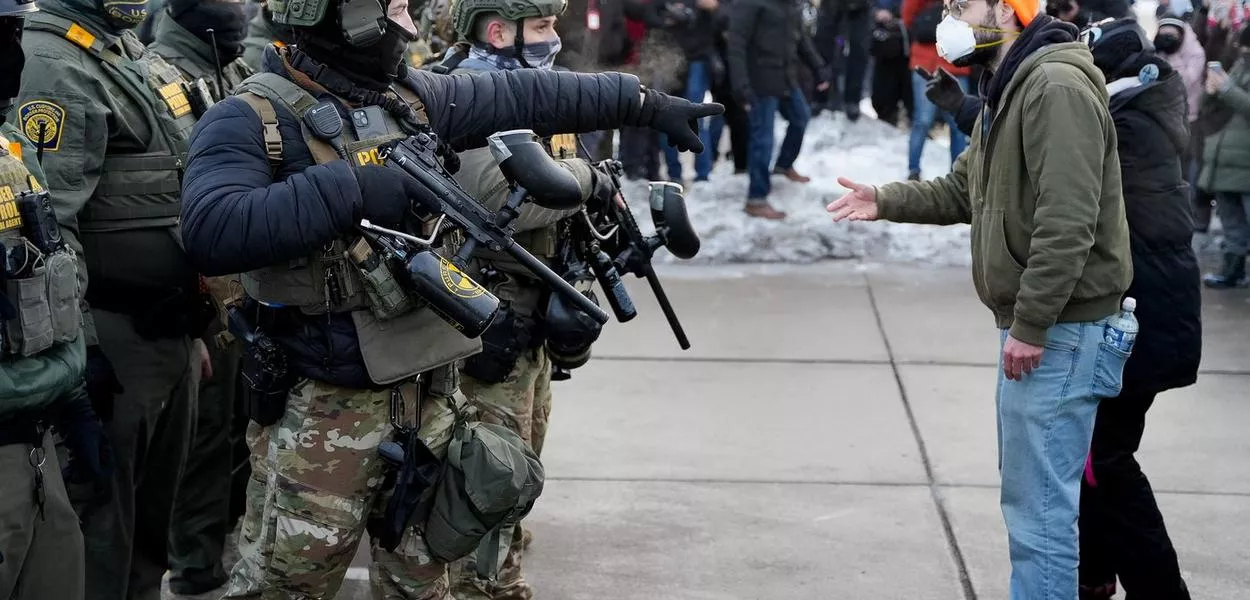 Agente federal e manifestante gesticulam durante protesto contra o assassinato de Renee Nicole Good em Minneapolis, Minnesota, EUA - 8 de janeiro de 2026