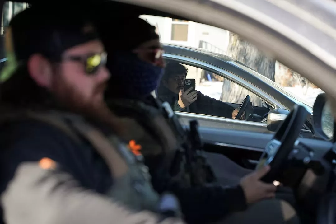 Um morador da comunidade filma agentes federais realizando uma ação de fiscalização migratória em Saint Paul, Minnesota, Estados Unidos