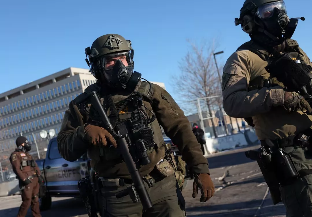 Membros das forças de segurança fazem guarda enquanto pessoas protestam em frente ao Edifício Federal Bishop Henry Whipple, em Minneapolis, Minnesota, Estados Unidos, em 30 de janeiro de 2026