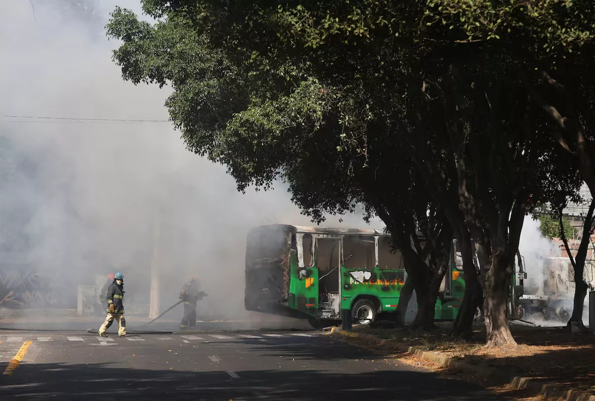 Bombeiros trabalham para extinguir as chamas de um veículo utilizado por integrantes do crime organizado como bloqueio de estrada após uma série de detenções realizadas por forças federais, em Guadalajara, México, em 22 de fevereiro de 2026