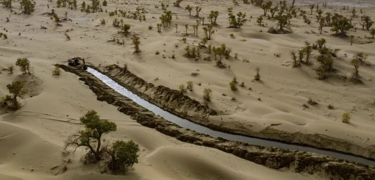 Foto aérea tirada por drone em 19 de setembro de 2025 mostra canal ecológico artificialmente escavado para desvio de enchentes e reabastecimento de água no Deserto de Taklimakan, no Condado de Yuli, Prefeitura Autônoma Mongol de Bayingolin, Região Autônoma Uigur de Xinjiang, noroeste da China. 