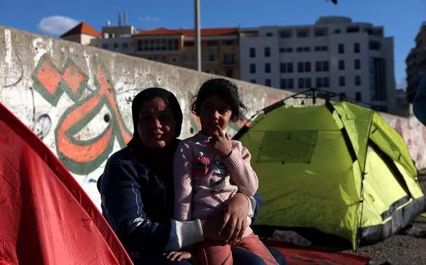 Uma mulher deslocada e sua filha sentam-se do lado de fora de uma tenda em Beirute, Líbano, em 8 de março de 2026