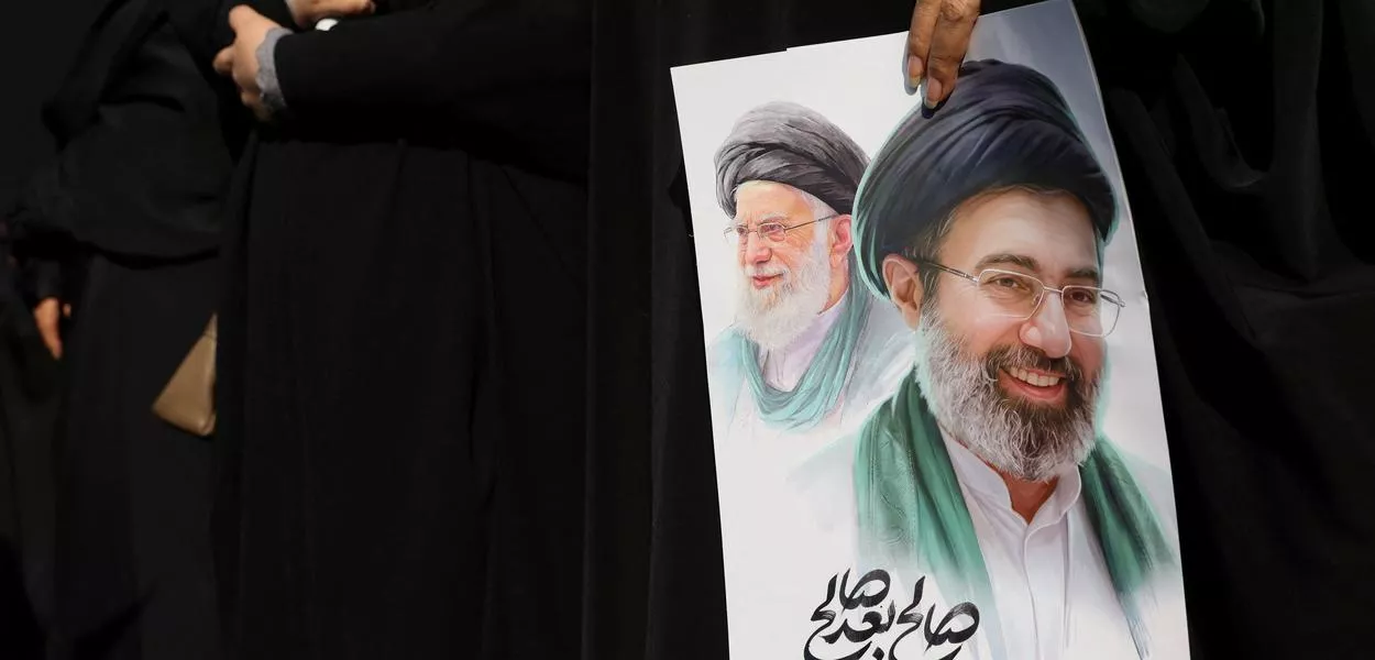 Mulher segura imagem do novo líder supremo do Irã, Mojtaba Khamenei, e do líder anterior, o aiatolá Ali Khamenei, durante cerimônia fúnebre para comandantes militares iranianos
11 de março de 2026
Majid Asgaripour/WANA via REUTERS