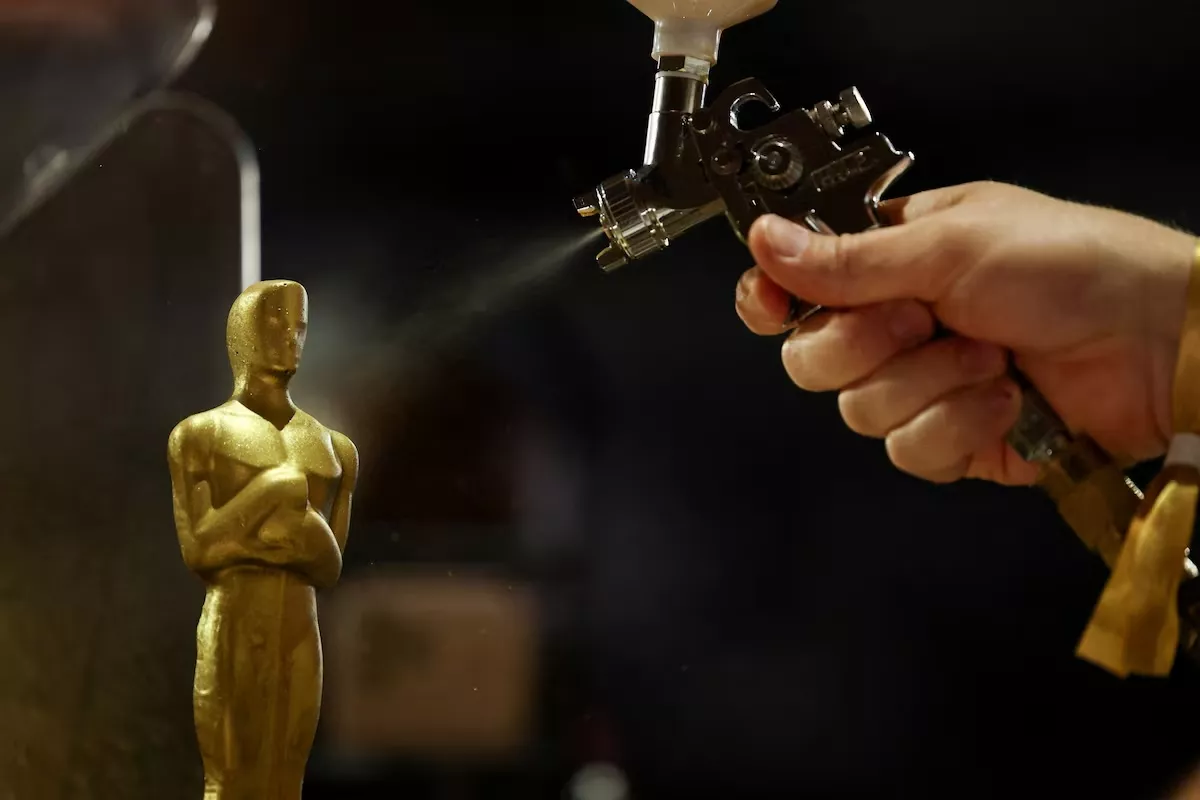 Uma pessoa pinta com spray uma estátua de chocolate em forma de Oscar
