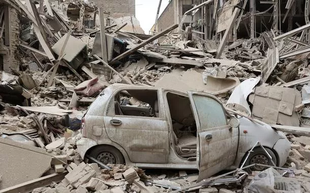 Um veículo destruído entre os escombros no local de um ataque a um prédio residencial, em meio ao conflito entre EUA e Israel com o Irã, em Teerã, Irã, 16 de março de 2026