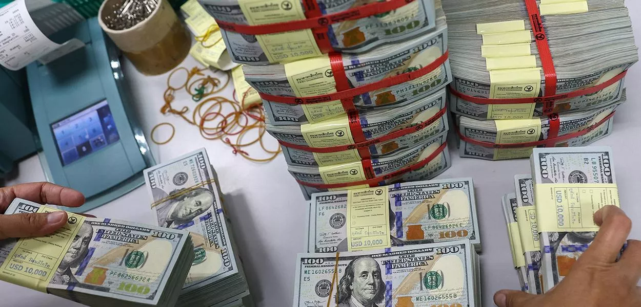 Funcionário de banco recolhe notas de dólar em agência em Bangkok, Tailândia, em 26 de janeiro de 2023