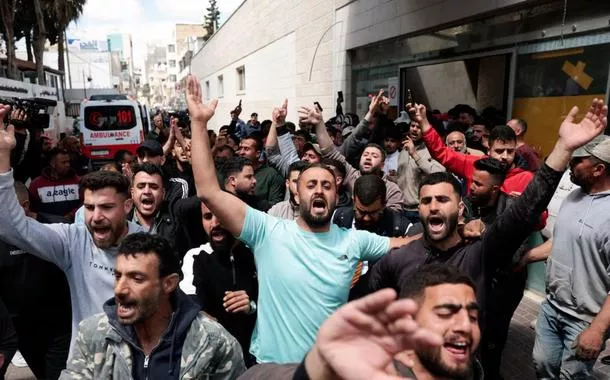 Pessoas reagem enquanto os corpos de dois palestinos, mortos durante um ataque de colonos israelenses, são transportados em um hospital em Ramallah, na Cisjordânia ocupada por Israel, em 21 de abril de 2026