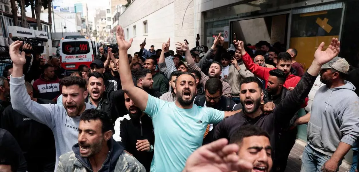 Pessoas reagem enquanto os corpos de dois palestinos, mortos durante um ataque de colonos israelenses, são transportados em um hospital em Ramallah, na Cisjordânia ocupada por Israel, em 21 de abril de 2026