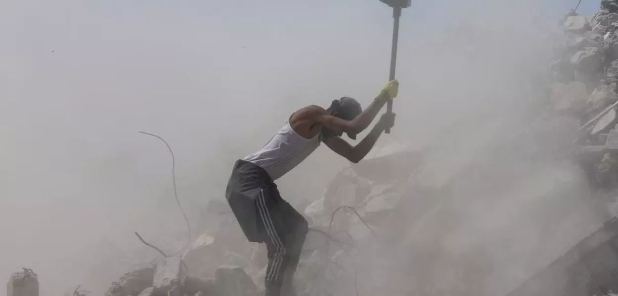 Um trabalhador palestino quebra concreto enquanto trabalha entre os escombros em Khan Younis, no sul da Faixa de Gaza, em 19 de abril de 2026
