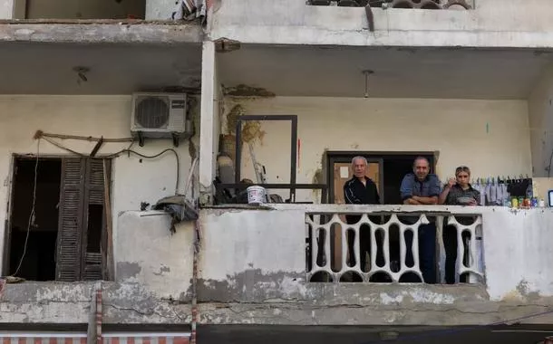 Pessoas estão sentadas em uma varanda próxima ao local de um ataque israelense  em 6 de maio de 2026