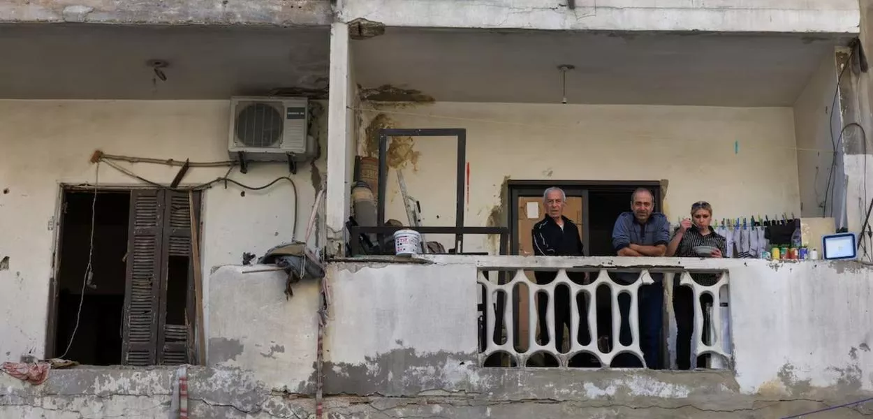 Pessoas estão sentadas em uma varanda próxima ao local de um ataque israelense  em 6 de maio de 2026