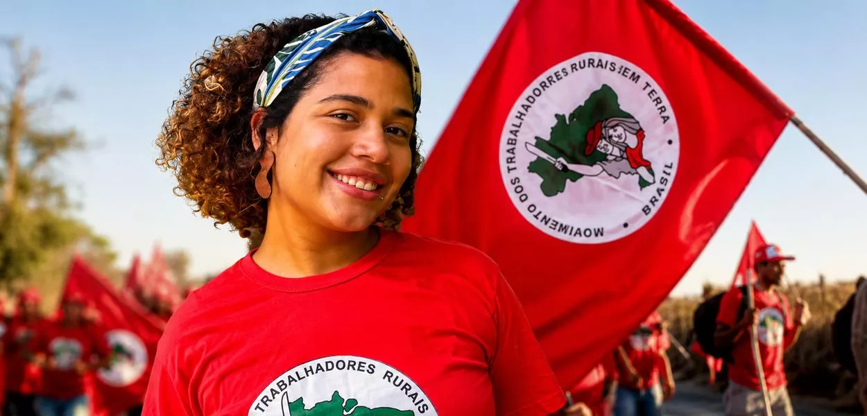 Parlamentar Maíra do MST e uma bandeira com integrantes do movimento