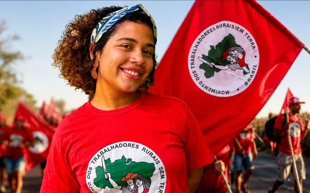 Parlamentar Maíra do MST e uma bandeira com integrantes do movimento
