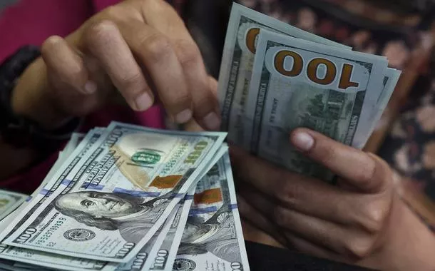 Pessoa conta notas de dólar americano em uma casa de câmbio em Jacarta, Indonésia, em 9 de abril de 2025. Foto tirada através de um vidro