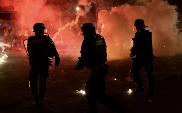 Policiais se protegem de sinalizadores após o Paris Saint-Germain vencer a Liga dos Campeões da UEFA