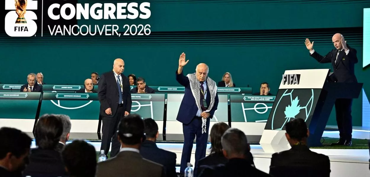 Jibril Rajoub, presidente da Federação Palestina de Futebol, reage no palco enquanto Moshe Zuares, presidente da Federação Israelense de Futebol, e o presidente da FIFA, Gianni Infantino, observam